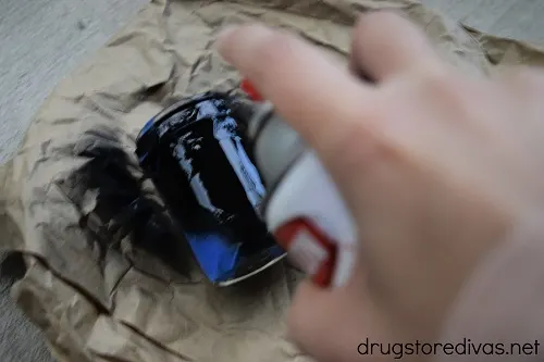 A can of spray paint spraying a mason jar.