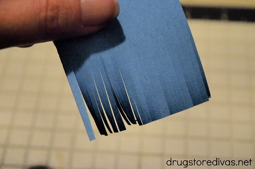 A blue card stock square cut into slits.