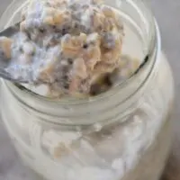 A spoon lifting overnight oats out of a mason jar with the words 