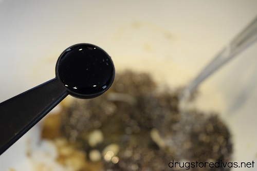Vanilla extract in a measuring spoon being poured into a bowl.