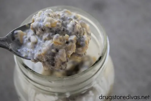A spoon lifting overnight oats out of a mason jar.