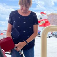 A woman pumping gas at a Buc-ees gas station with the words 