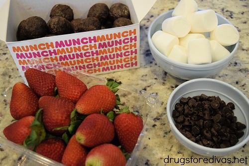 Chocolate munchkins, marshmallows, strawberries, and chocolate chips on a counter.