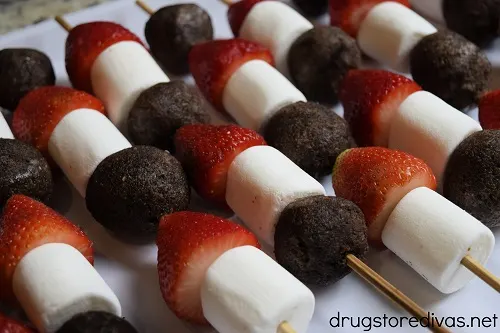 Skewers with Chocolate Munchkins, strawberries, and marshmallows on a tray.