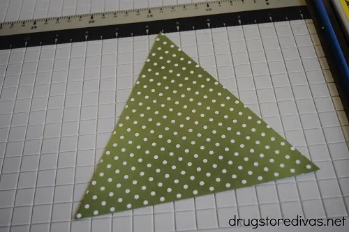 A triangle of scrapbook paper on a paper trimmer.