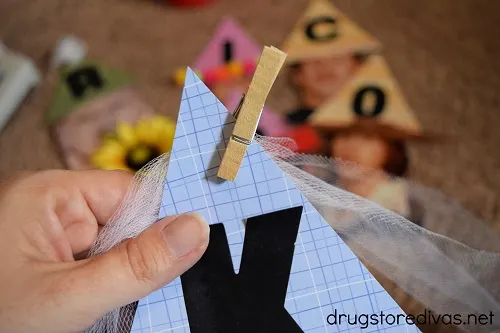 A scrapbook party hat attached to tulle by a clothespin.
