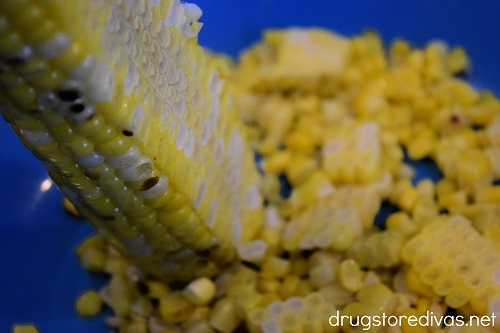Corn being cut from a husk into a bowl.
