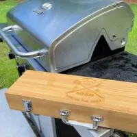 A grill, with a box of grilling tools next to it, and the words 