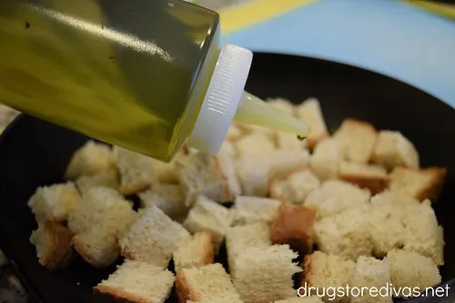 Olive oil being drizzled on diced bread.