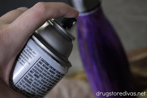 A spray can aimed at a water bottle.