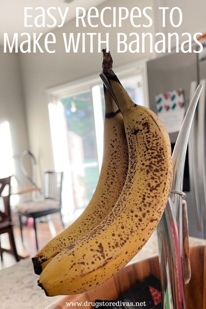 Two ripe bananas hanging in a fruit bowl in a kitchen with the words "Easy Recipes To Make With Bananas" digitally written on top.
