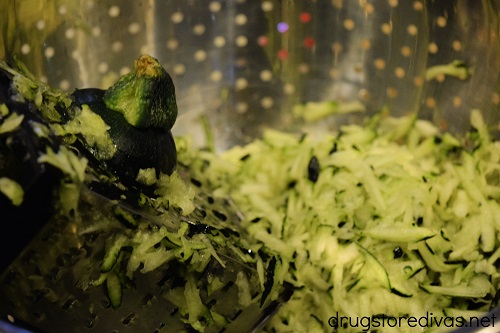 Zucchini being grated in a colander.