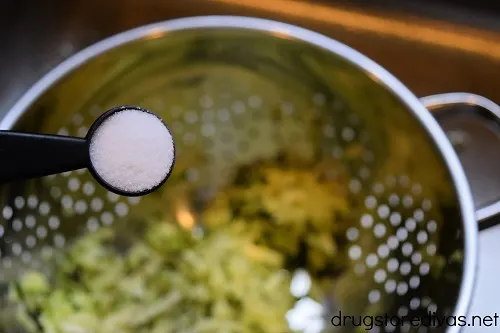Salt in a measuring spoon being sprinkled over salt.