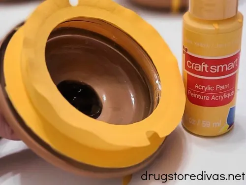 Yellow paint on a jar's lid next to a tube of yellow paint.