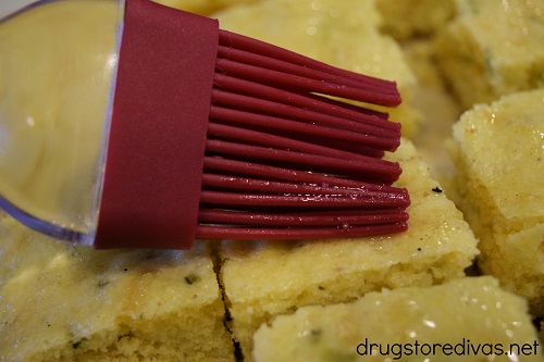 Cornbread being brushed with a pastry brush.