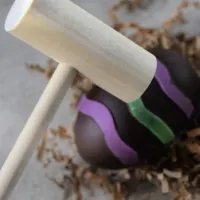 A wooden mallet smashing a chocolate egg with the words 