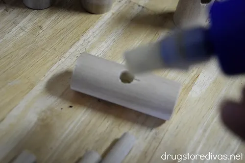Wood glue being squeezed into a wooden dowel with a hole in it.