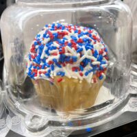A cupcake with red, white, and blue sprinkles with the words 