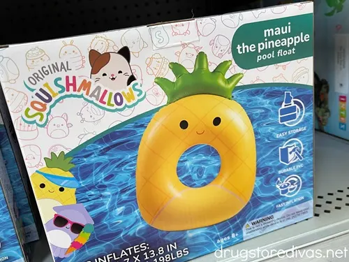 A Squishmallows pineapple pool float in a box on a shelf in a store.
