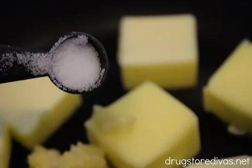 Salt being poured on top of butter and garlic in a pan.