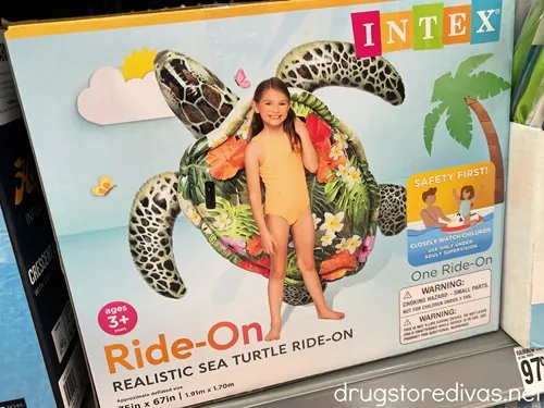 A box containing a turtle pool float on a shelf in a store.