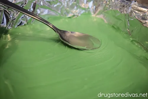 A spoon spreading green fudge in a pan.