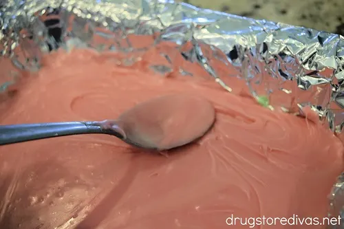 A spoon spreading pink fudge in a pan.