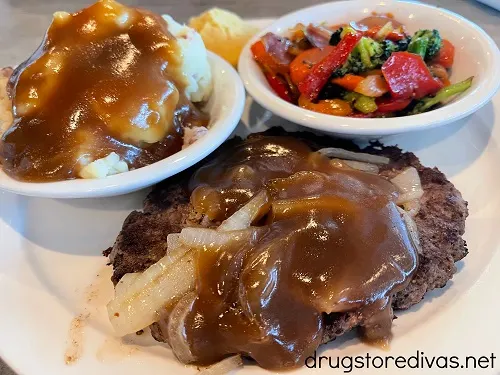 Hamburger steak, mashed potatoes, and vegetables on a plate.