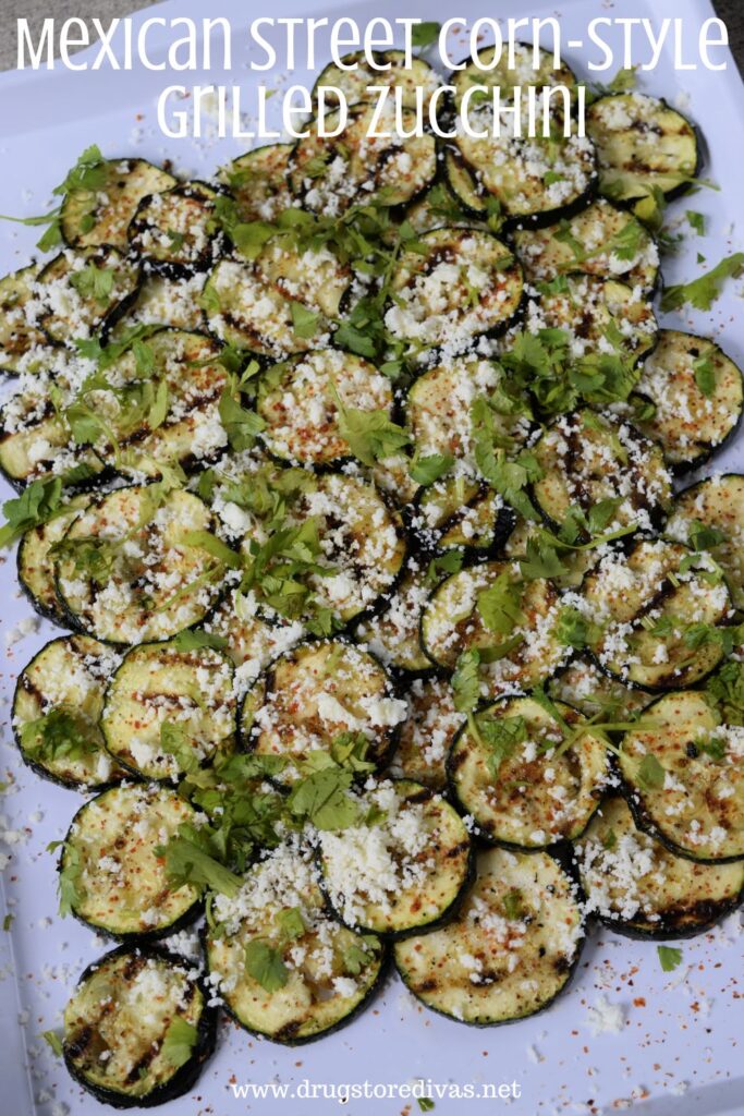 Grilled zucchini on a tray with the words "Mexican Street Corn-Style Grilled Zucchini" digitally written on top.