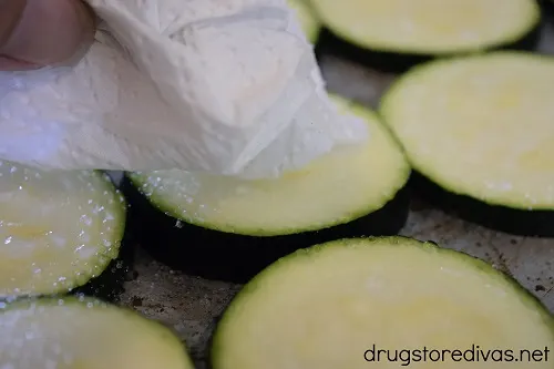 Zucchini being blotted with a paper towel.