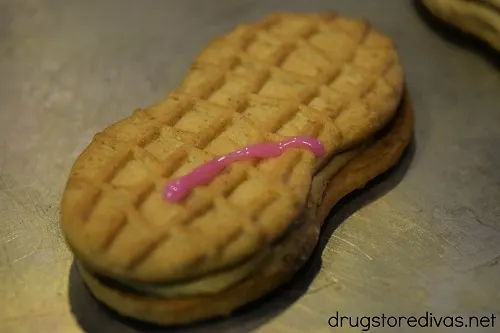 A pink line of icing on a Nutter Butter cookie.