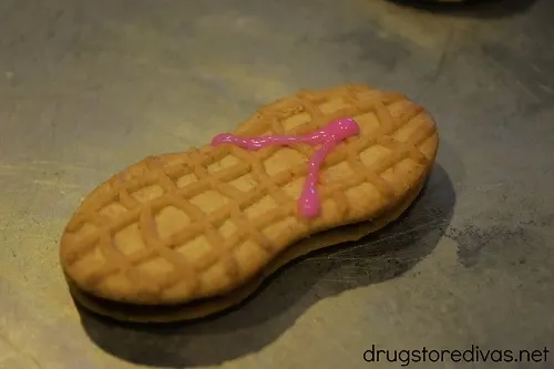 Two pink lines of icing on a Nutter Butter cookie.