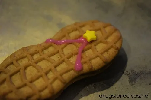 Two pink lines of icing and a star sprinkle on a Nutter Butter cookie.