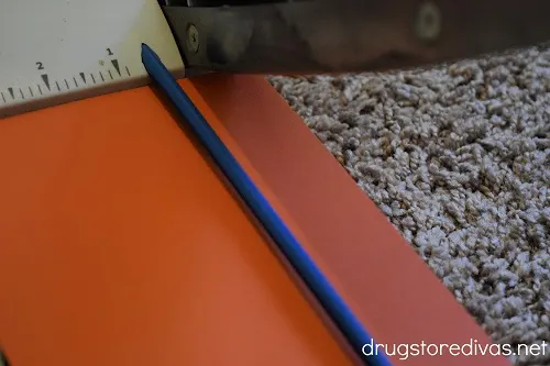 Orange scrapbook paper being cut in a paper trimmer.