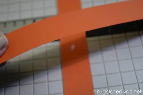 Two strips of orange paper being glued together.