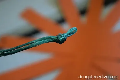 A knot tied at the bottom of a piece of green twine.
