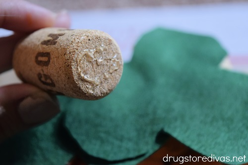 A wine cork with glue on it above felt leaves.