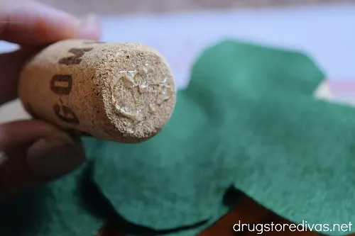 A wine cork with glue on it above felt leaves.