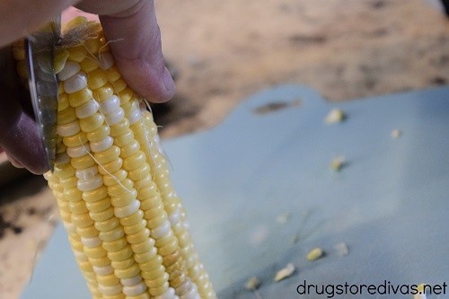 An ear of corn being cut in half.