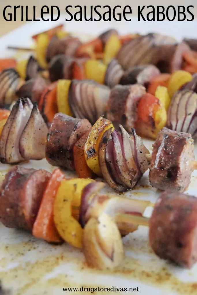 Five sausage and veggie skewers on a plate with the words "Grilled Sausage Kabobs" digitally written on top.