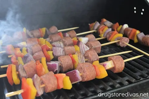 Sausage and vegetable skewers on a grill.