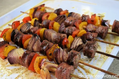 Sausage and vegetable skewers on a tray.