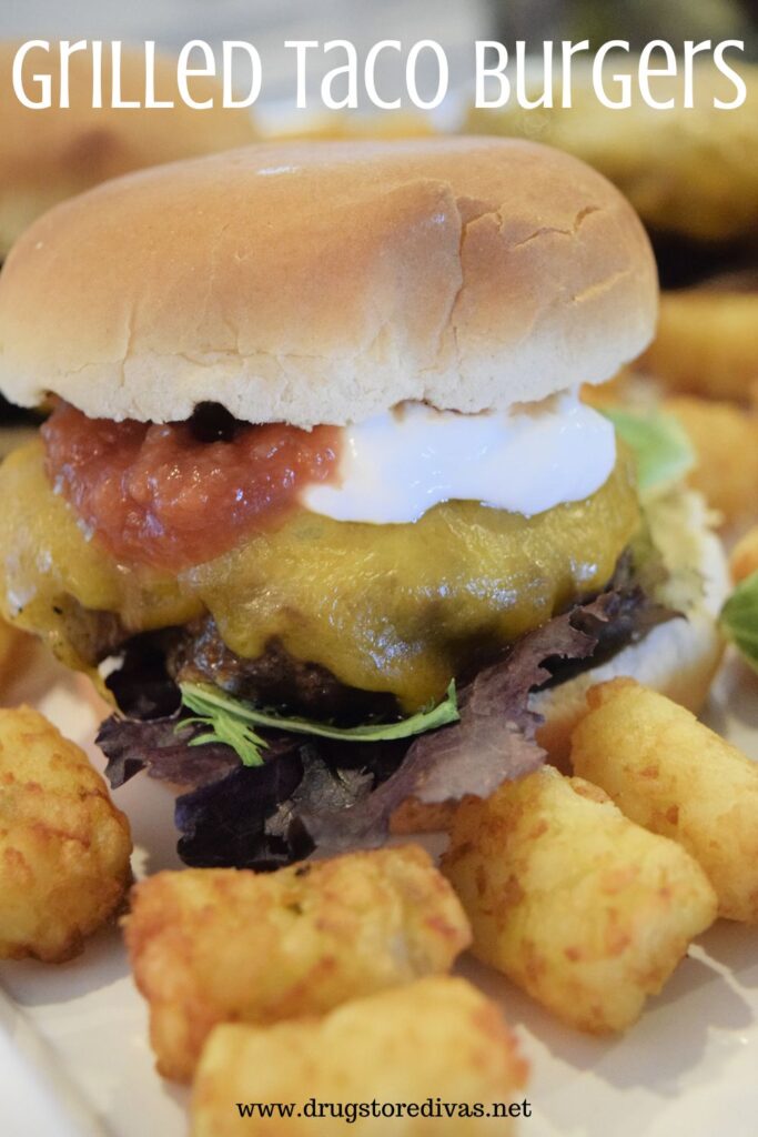 A taco burger with tater tots and the words "Grilled Taco Burgers" digitally written on top.