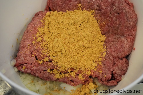 Taco seasoning, meat, and diced onions in a bowl.