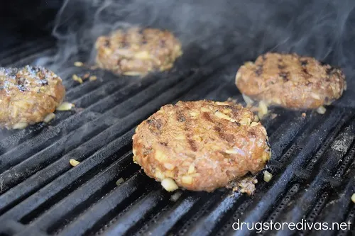 Four cooked burger patties on a grill.