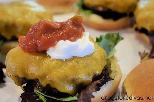 Grilled taco burgers with salsa and sour cream on top.