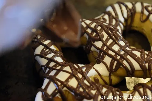 Melted chocolate being drizzled on a soft pretzel with marshmallow creme on it.