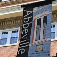 A sign on a pole saying Abbeville with the words 