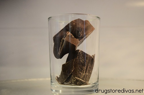 Chocolate almond bark pieces in a glass in the microwave.
