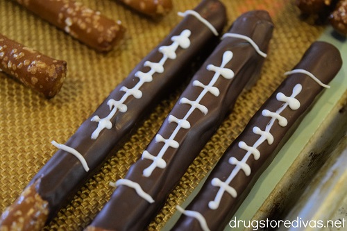 Chocolate football pretzel rods on a cookie sheet.